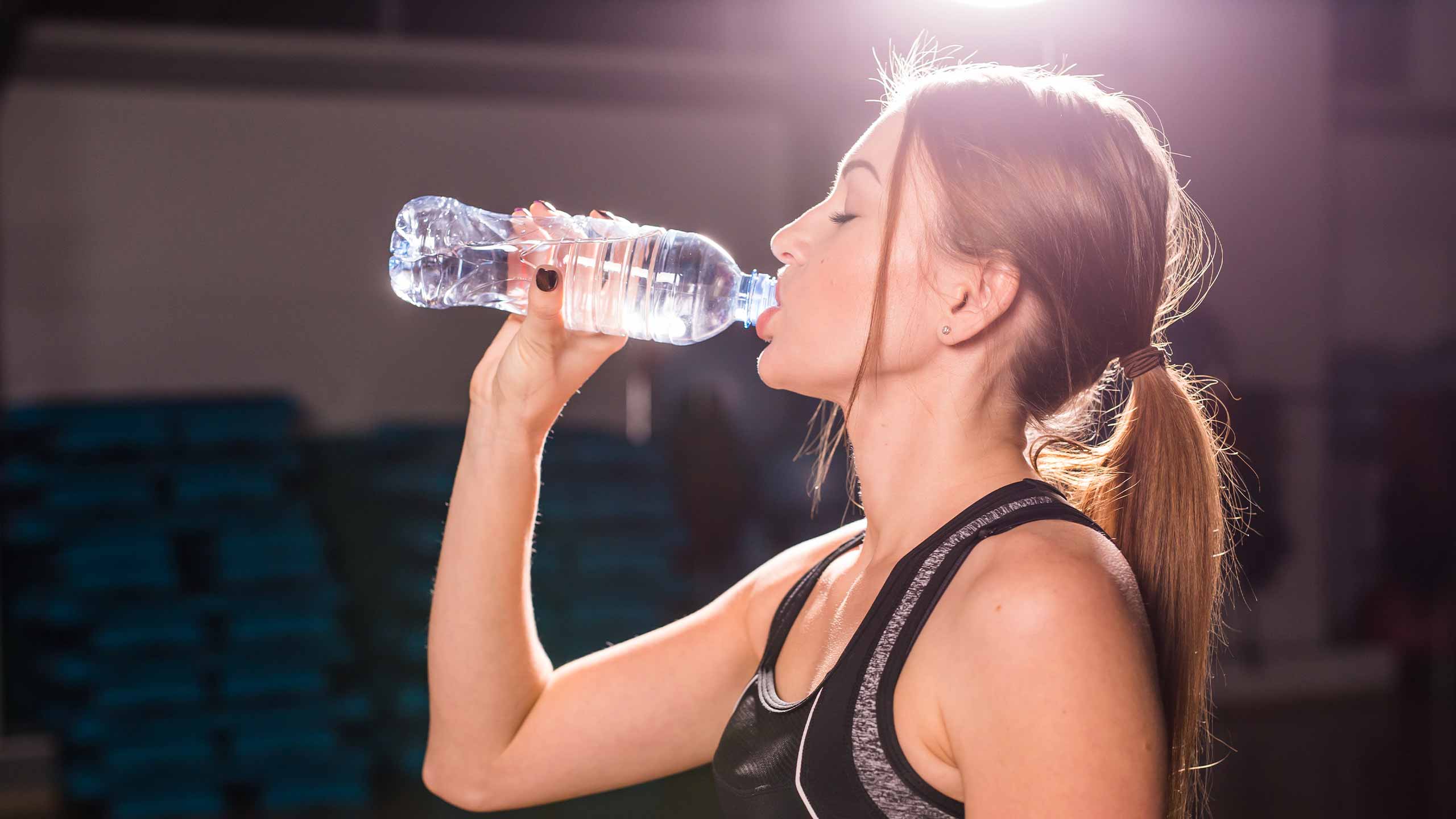 Frau trinkt im Fitnessstudio