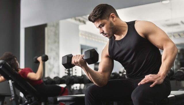 Mann der Bizeps trainiert im Fitnesstudio balance